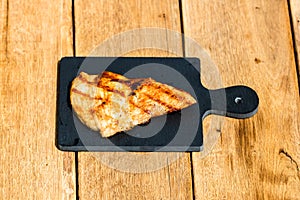 Close up of grilled steak on small black chopping board isolated. Barbecue, grill and food concept