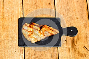 Close up of grilled steak on small black chopping board isolated. Barbecue, grill and food concept