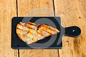 Close up of grilled steak on small black chopping board isolated. Barbecue, grill and food concept