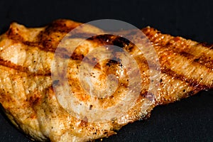 Close up of grilled steak on small black chopping board isolated. Barbecue, grill and food concept