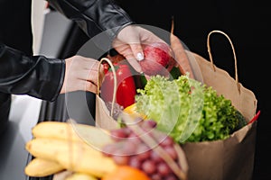 Close-up of groceries in eco package in car trunk. Hands of female packing vegetables and fruits after shipping in