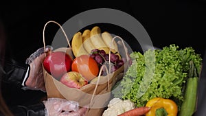 Close-up of groceries in eco package in car trunk. Hands of female packing vegetables and fruits after shipping in