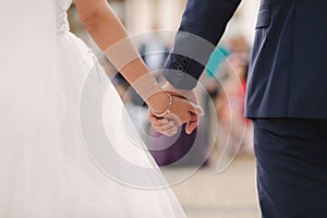 Close up of groom hold bride`s hand in front of guests. Wedding ceremony. Back view