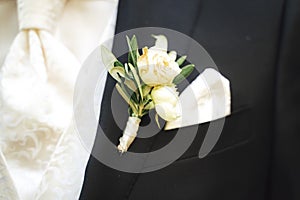 Close up of groom`s white flower wedding boutonniere. White color suits to other accessories. Wedding day concept.