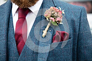 Close up of groom wearing tweed suit and boutonniere