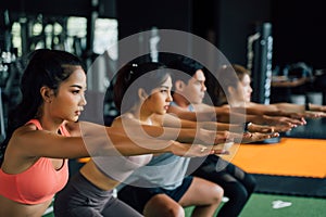 Close-up of Group of athletic young Asian people in sportswear doing squat and exercising at the gym.