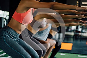 Close-up of Group of athletic young Asian people in sportswear doing squat and exercising at the gym.