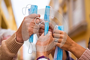 Close up of a group of four hands together holding a medical and surgical mask after winnig covid-19 and be free and can no wear photo