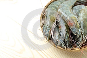 Close up group of fresh raw pacific white shrimp in bamboo bowl on wooden table