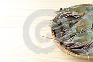 Close up group of fresh raw pacific white shrimp in bamboo bowl on wooden table