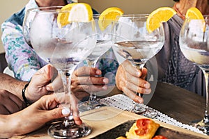 Close up of group of people friends or family celebrate together drinking cocktails or wines from big glass - home or restaurant