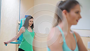 Close-up A group of three girls doing exercises - stretch hands rubber blue expanders.