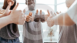 close up. group of youth standing in a circle and showing thumbs up.