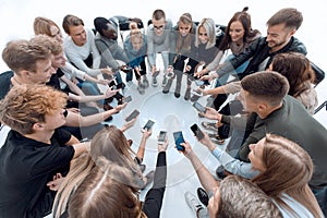 close up. groups of young people with smartphones sitting in a circle