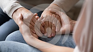 Closeup image adult daughter holding hands of old mother