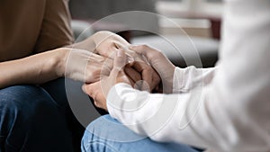 Close up grownup daughter comforting, holding mature mother hands