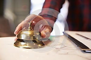 Close Up Of Guest's Hand On Hotel Reception Bell