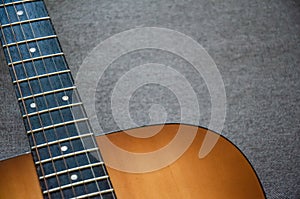 Close-up guitar fretboard with strings isolated on a blurred gray background with copy space. Music concept. Guitar neck texture.