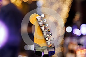 Close-up of guitar neck pegs. Guitar on stage illuminated with concert lights