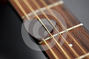 close up of guitar neck with pick between strings