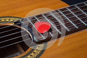 Close-up of a guitar pick on the strings of a classical guitar.