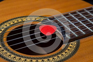 Close-up of a guitar pick on the strings of a classical guitar.