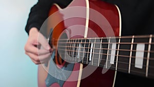 Close-up of the guitar playing against a bright background. Learning to play the guitar at home.