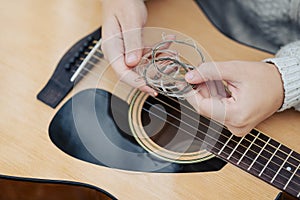 Close up on guitar strings in hands of a girl guitarist