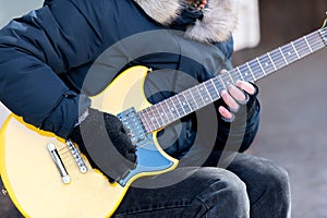 Close-up of guitarist male hand in black glove who touches string on yellow six string guitar