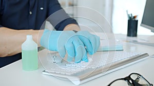 Close-up of guy`s hands wet wiping computer keyboard at work using sanitizer