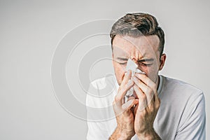 Close up of guy in white t-shirt sneezing to handkerchief and wiggling at the samte time. He has a nose infection.