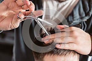 Close-up Hair cutting with metal scissors. Master cuts hair and beard of men in the barbershop, hairdresser makes