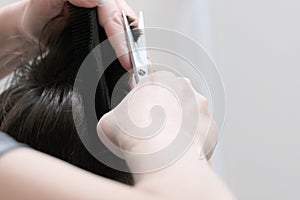 Close-up of haircuts in a hairdresser. Female hands with scissors cut off the ends of the hair on the guy`s head.