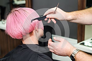 Close up of hairdresser is combing client`s pink hair in hair salon