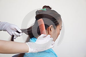 Close up hairdresser is combing hair female client before doing hairstyle.