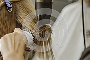 Close up of hairdresser hands drying human hair with equipment. Woman holding a comb. close-up. Macro photo