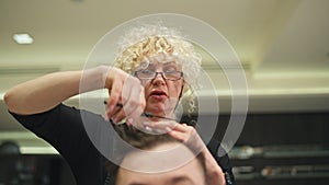 Close-up of hairdresser's hand cutting hair with scissors.