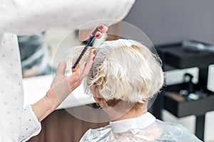 Close up of hairdresser`s hands are combing client`s hair at beauty salon