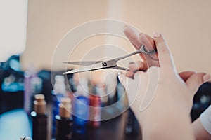 A close-up of hairdresser's holding scissors on the background