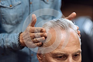 Close up of hairdresser using hair gel on client