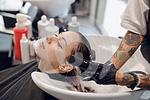 Close up of hairdresser is washing hair of young woman in beauty salon. High quality photo