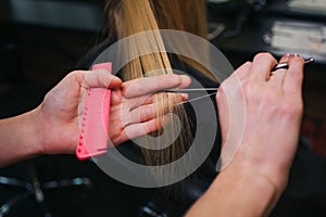 Close-up of hairdressers hand cutting blonde hair. Doing new haircut in beauty salon