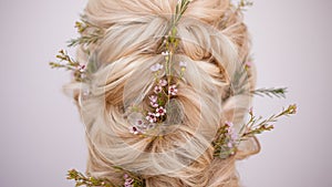 Close-up of hairstyles with weaving strands decorated with small flowers.