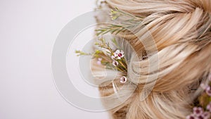 Close-up of hairstyles with weaving strands decorated with small flowers.