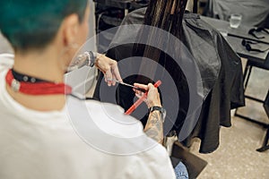 Close up of hairstylist trimming hair of customer in a beauty salon. Care and beauty hair products
