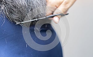 Close up of hairstylist trimming senior client hair. Professional hairstyler woman cutting hair of mature woman