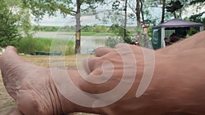 Close up of hairy man`s leg who scratches it. Defocused view of background