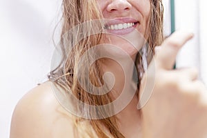 Close up half face cropped portrait of smiling woman& x27;s with wet hair after shower in shower cabin at home