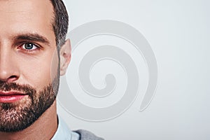 Close-up half face portrait of a smiling attractive man with a stubble looking at camera