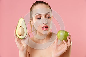 Close up half naked woman 20s perfect skin nude make up blue eyes hold in hand ripe avocado apple isolated on pastel